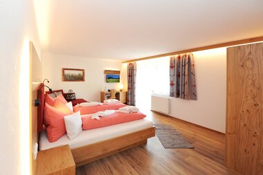 Helles geräumiges Zimmer mit einer Sitzgelegenheit eine Doppelbett sowie einen Zugang zum Balkon | © Hotel Eggerhof